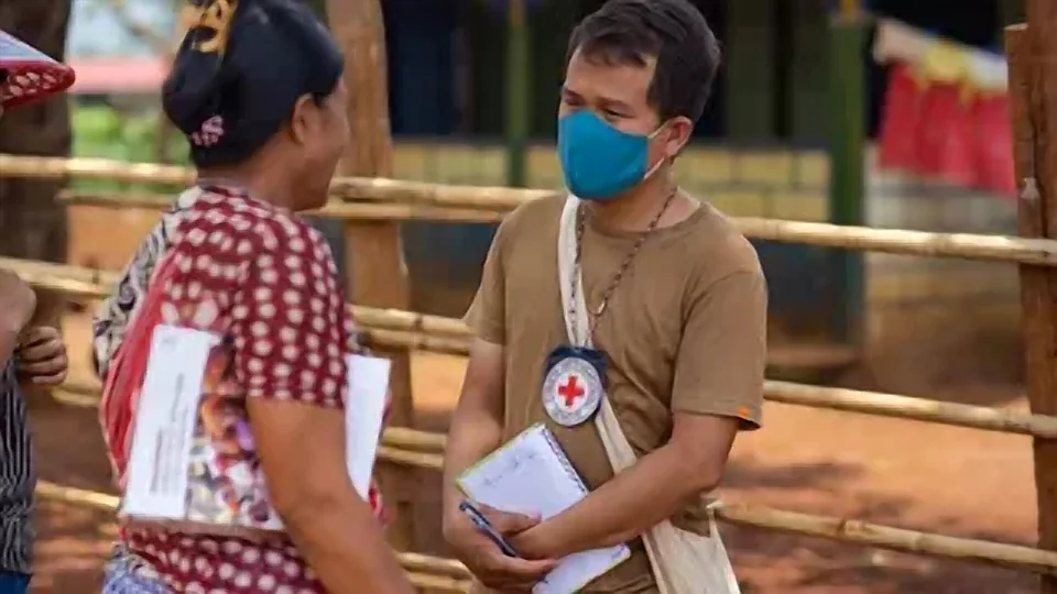 Representante humanitária conversando com pessoas em ambiente comunitário