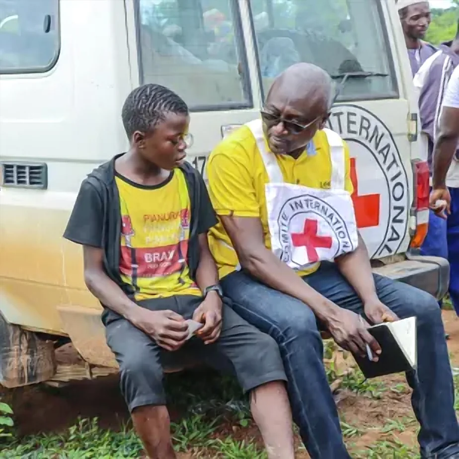 Voluntário da Cruz Vermelha sentado ao lado de um jovem, em momento de escuta e acolhimento